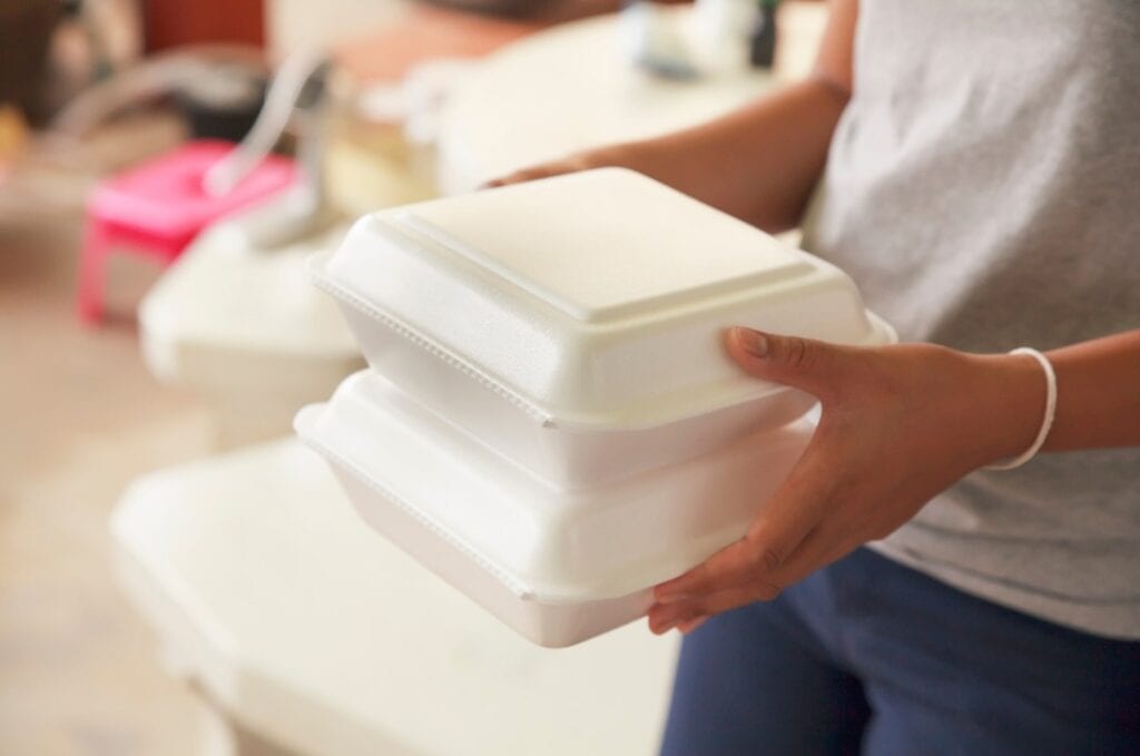 Frau mit Essensverpackungen aus Schaumstoff in der Hand